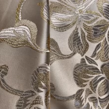 Tissu brodé motifs floraux dorés brillants.