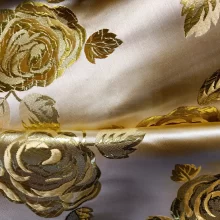 Tissu doré avec motifs de roses brodées.