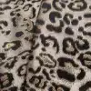 Tissu motif léopard noir et doré, gros plan.