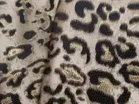 Tissu motif léopard noir et doré, gros plan.