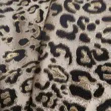 Tissu motif léopard noir et doré, gros plan.