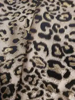 Tissu motif léopard noir et doré, gros plan.