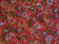 Tissu rouge avec motifs floraux brodés colorés.