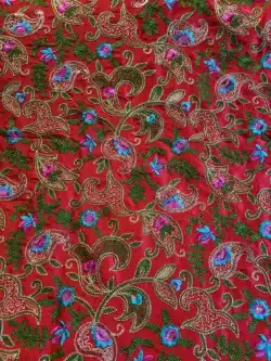 Tissu rouge avec motifs floraux brodés colorés.