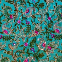 Tissu vert avec motifs floraux brodés colorés.